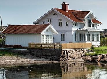 Foreclosee lists waterfront property for sale which consists of a white house with a red roof on the beach.